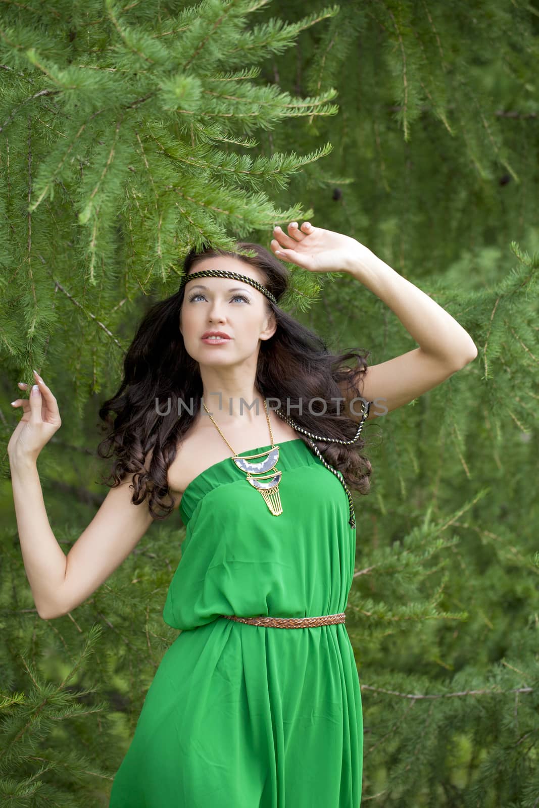 Beautiful young woman in green dress, against green of summer park