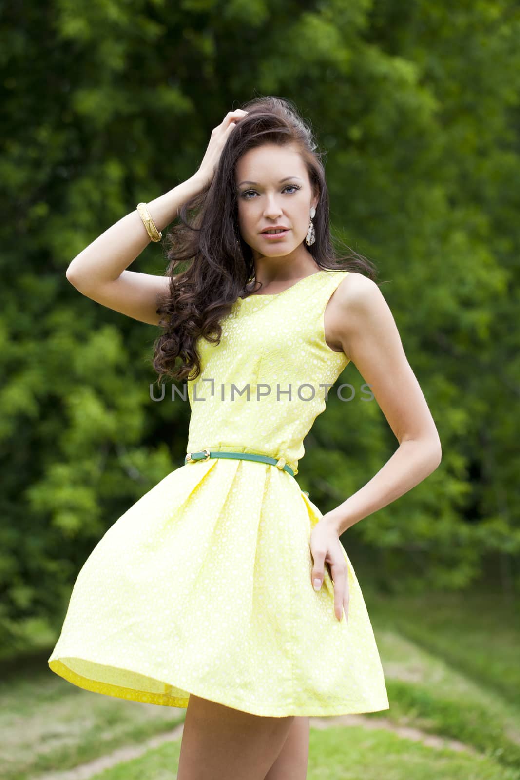 Beautiful young woman in green dress, against green of summer park