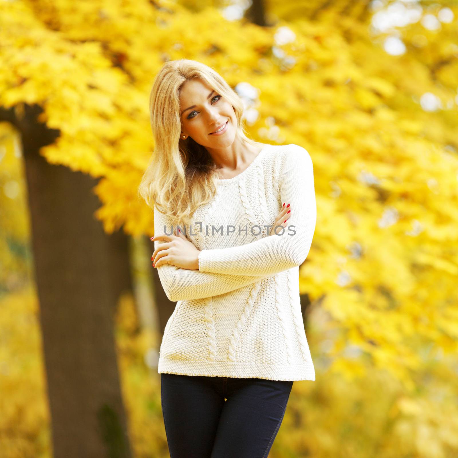Portrait of beautiful young woman walking outdoors in autumn park