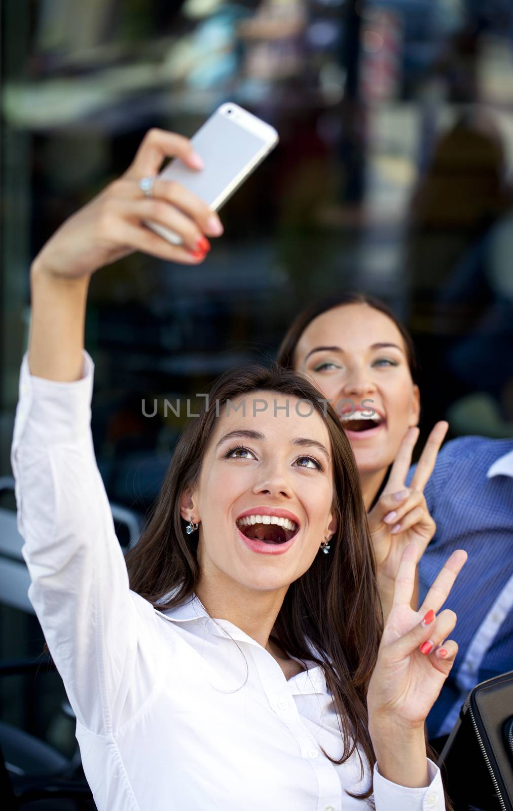 Selfie Two happy girlfriends sitting in a cafe on the street