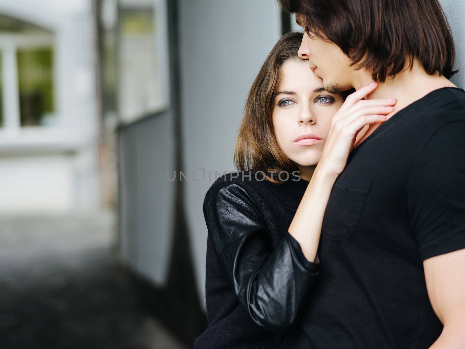 Photo of a young couple in love holding each other in an alley.
