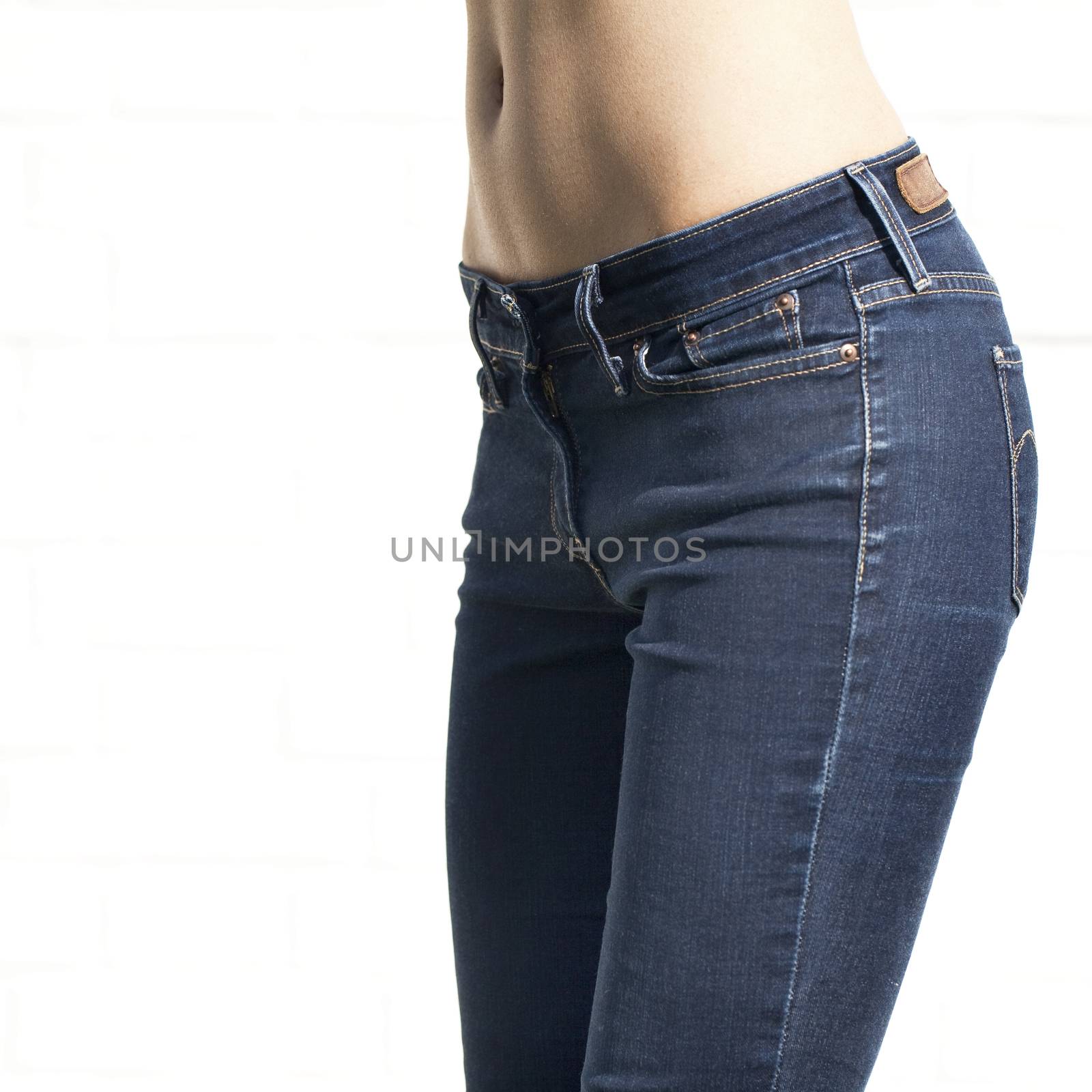 Woman in blue jeans with naked back isolated on white brick wall