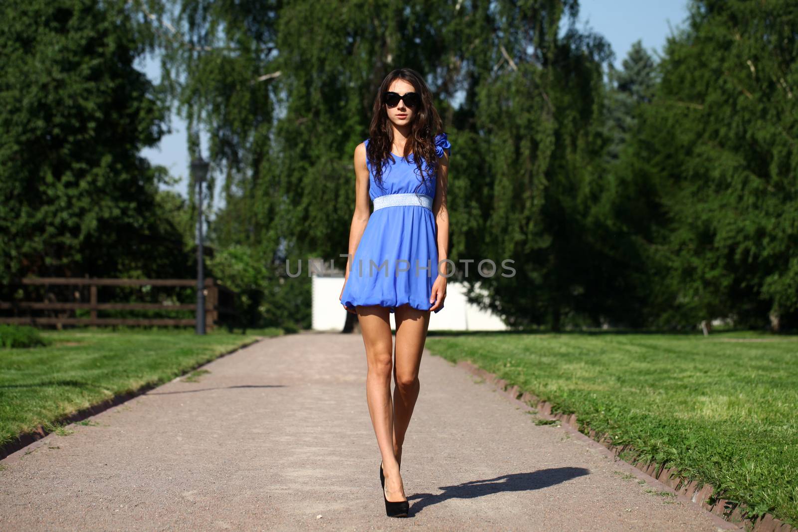 Beautiful young woman walking on the summer park