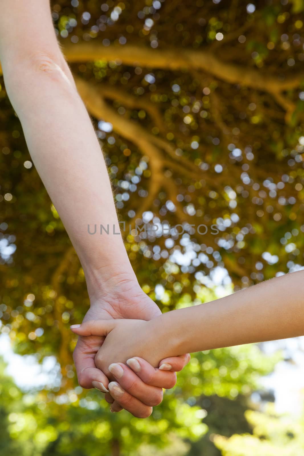 Extreme close-up of a mother holding a hand of her daughter outdoors