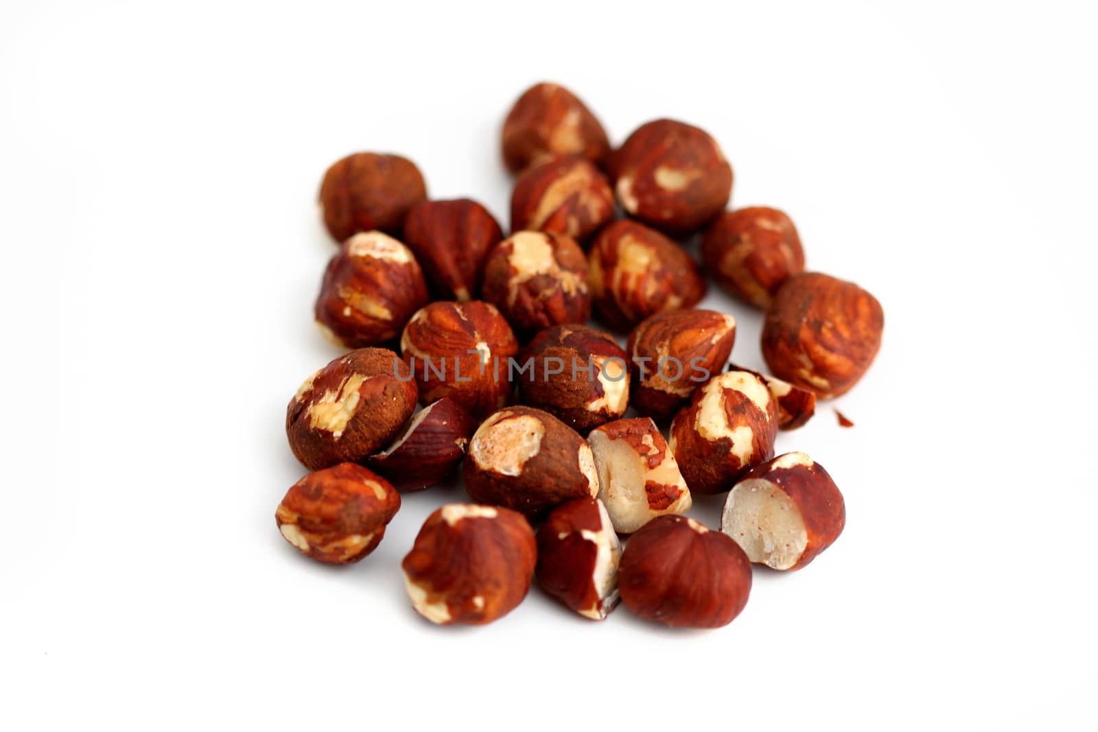 Pile of brown hazelnuts on white background.