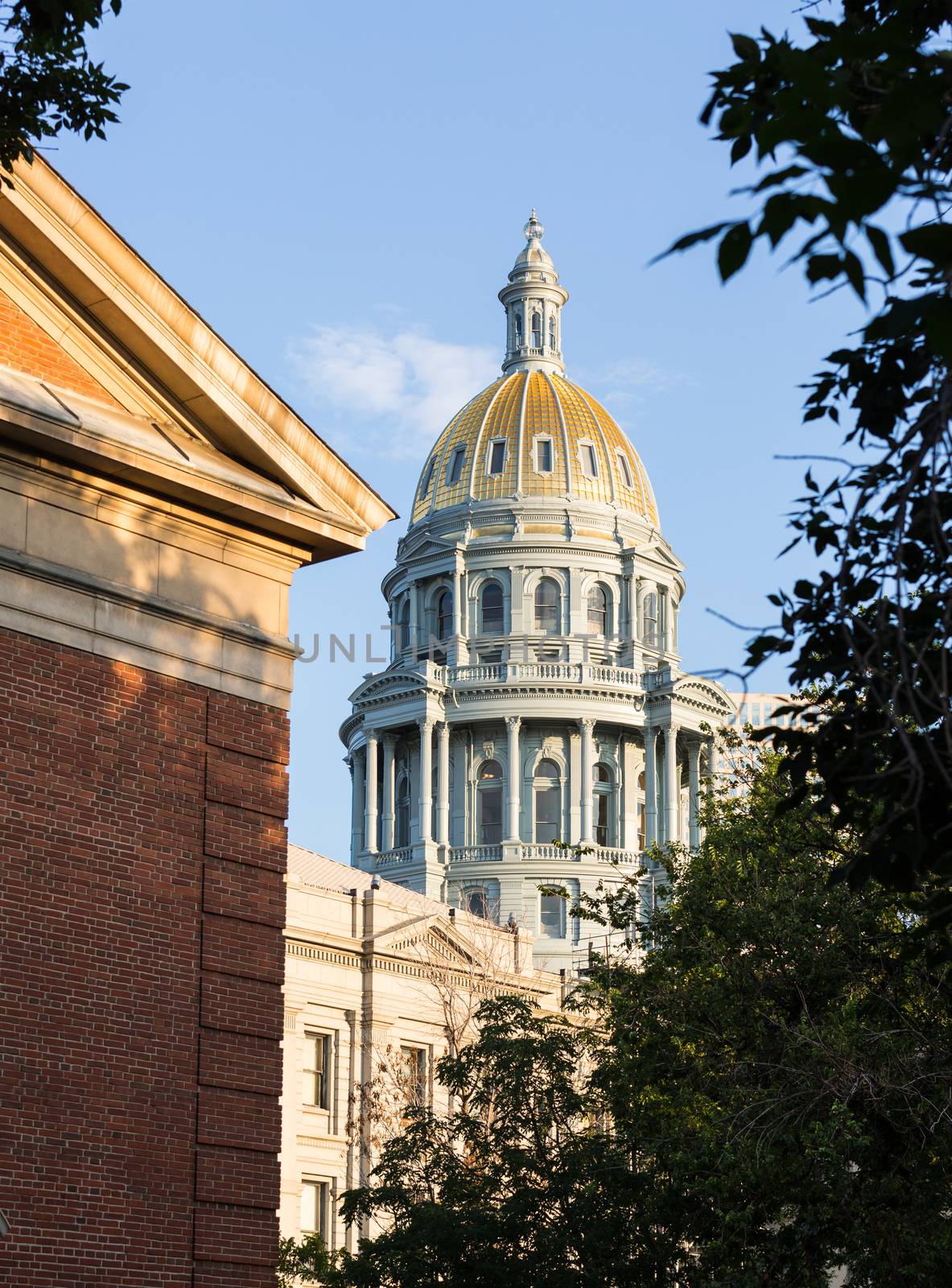 The gold leaf covered dome of the State Capitol Dome in Denver Colorado shortly after sunrise