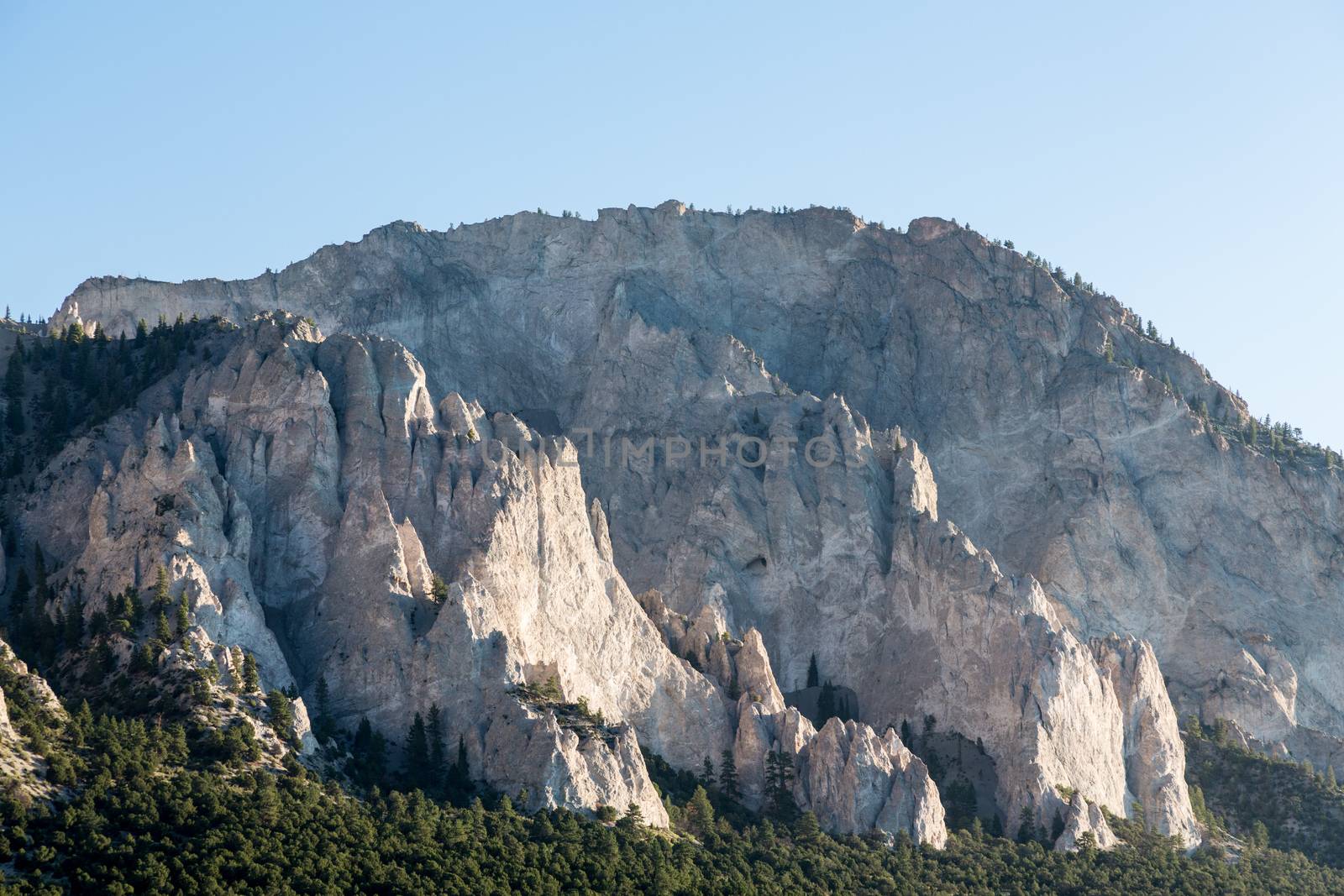Steep jagged spikes of  chalk white cliffs of Mount Princeton near Buena Vista in Colorado shortly after sunrise as the sun first lights the mountainside