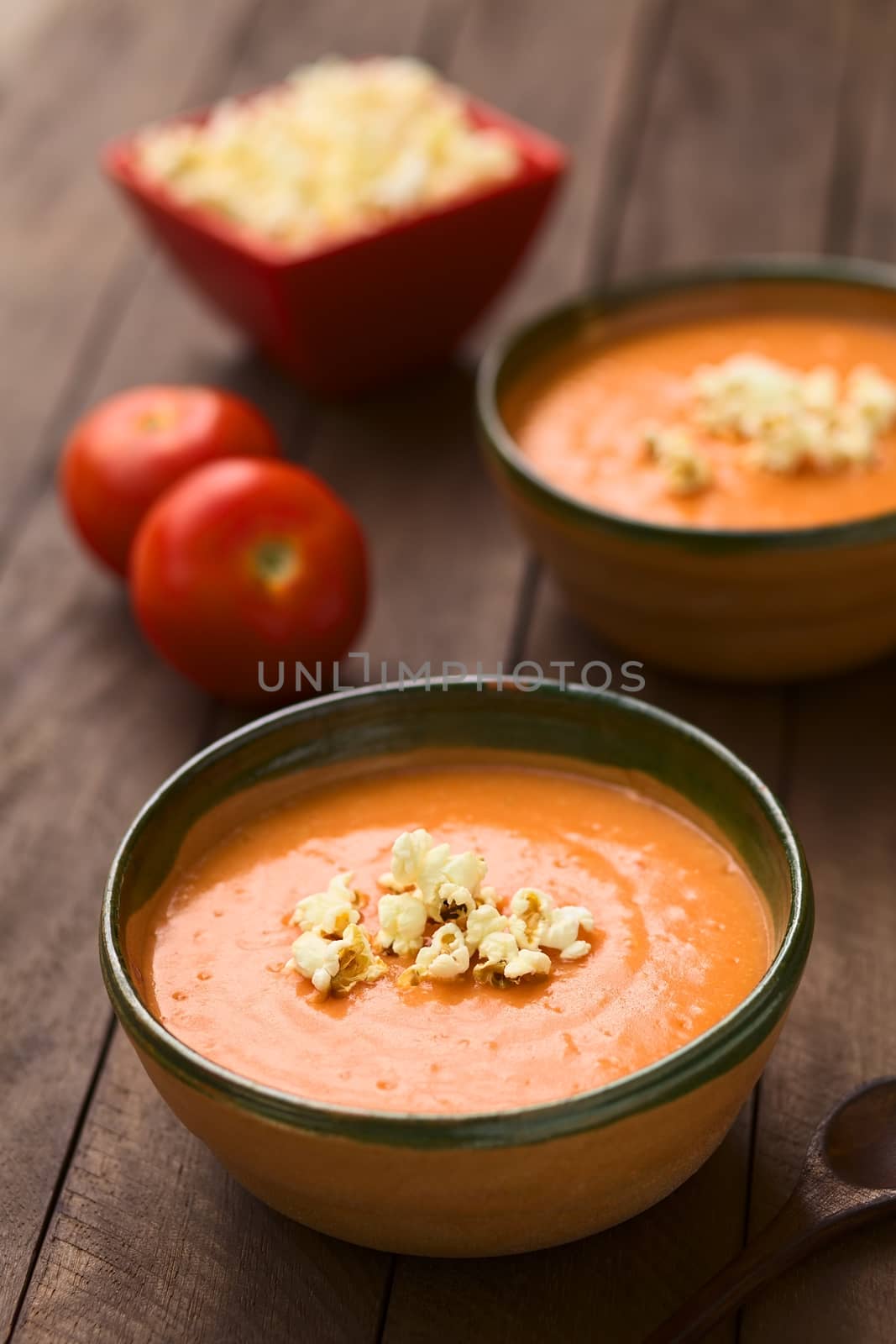 Ecuadorian tomato and potato cream soup served with popcorn on top in rustic bowls (Selective Focus, Focus on the front of the popcorn on the soup)