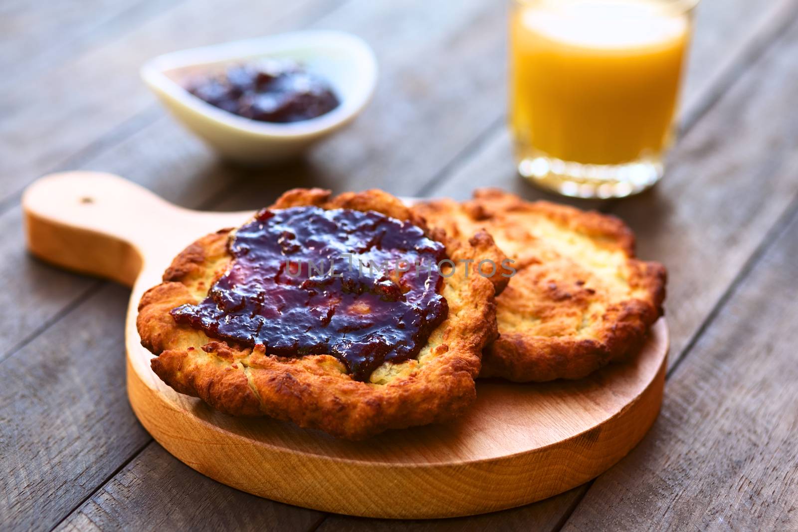 Freshly prepared traditional Hungarian deep fried flat bread called Langos made of a yeast dough, with jam spread on top  (Selective Focus, Focus on the front of the jam on the langos) 

 