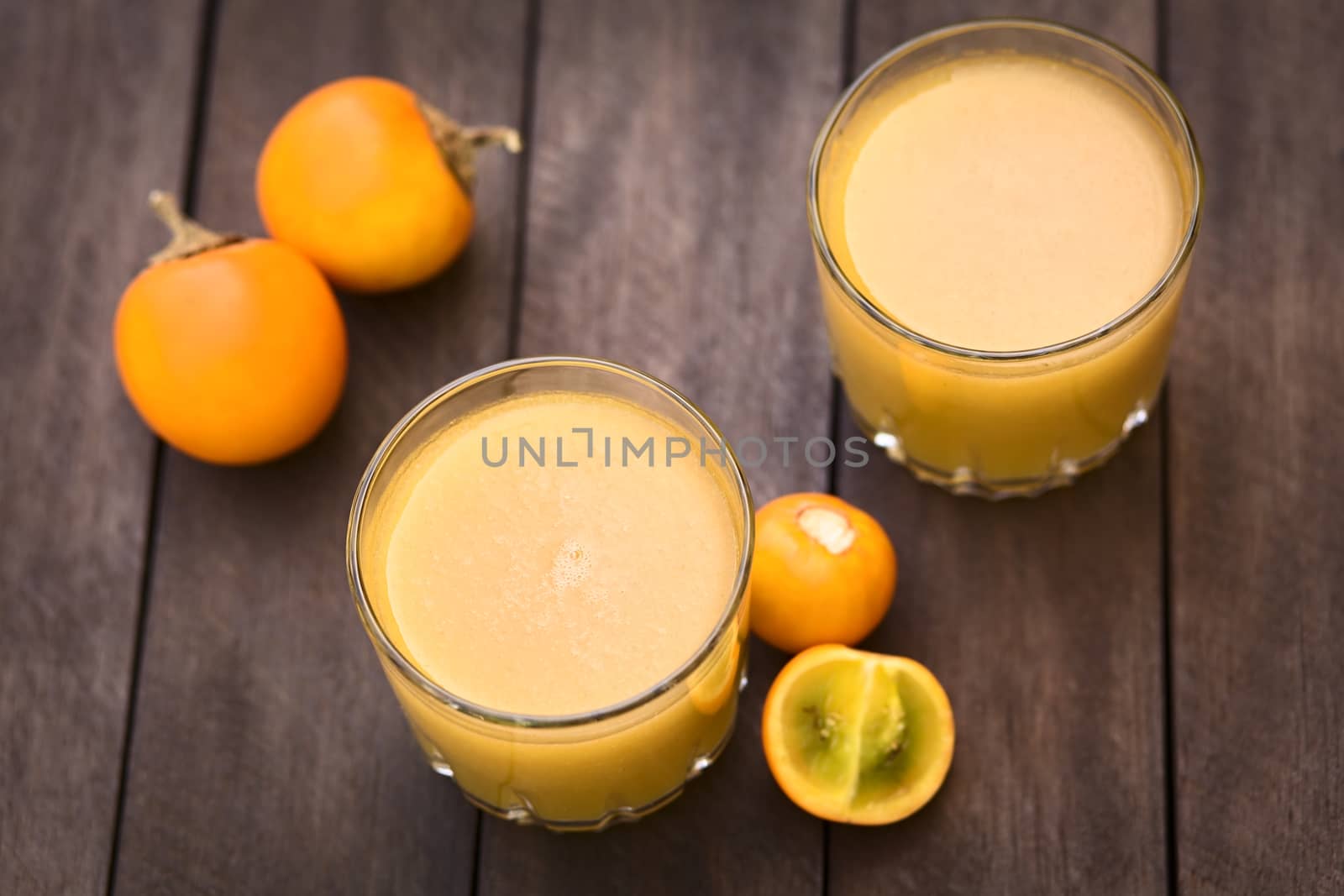 Freshly prepared juice out of Naranjilla or Lulo fruits (lat. Solanum quitoense) with fruits on the side (Selective Focus, Focus in the middle of the first juice) 
