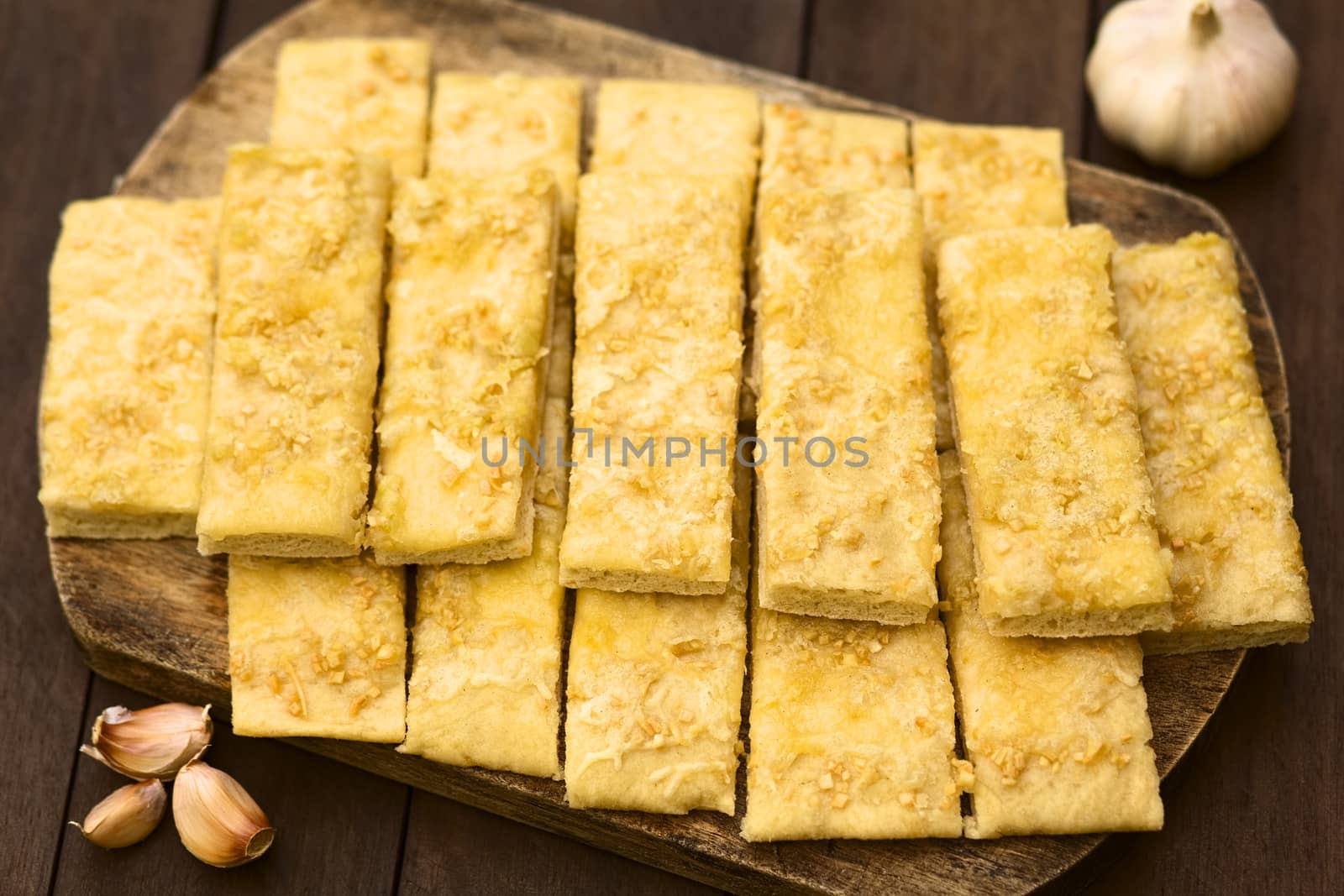 Fresh homemade garlic and cheese sticks made of a yeast dough served on wooden board (Selective Focus, Focus one third into the garlic sticks)