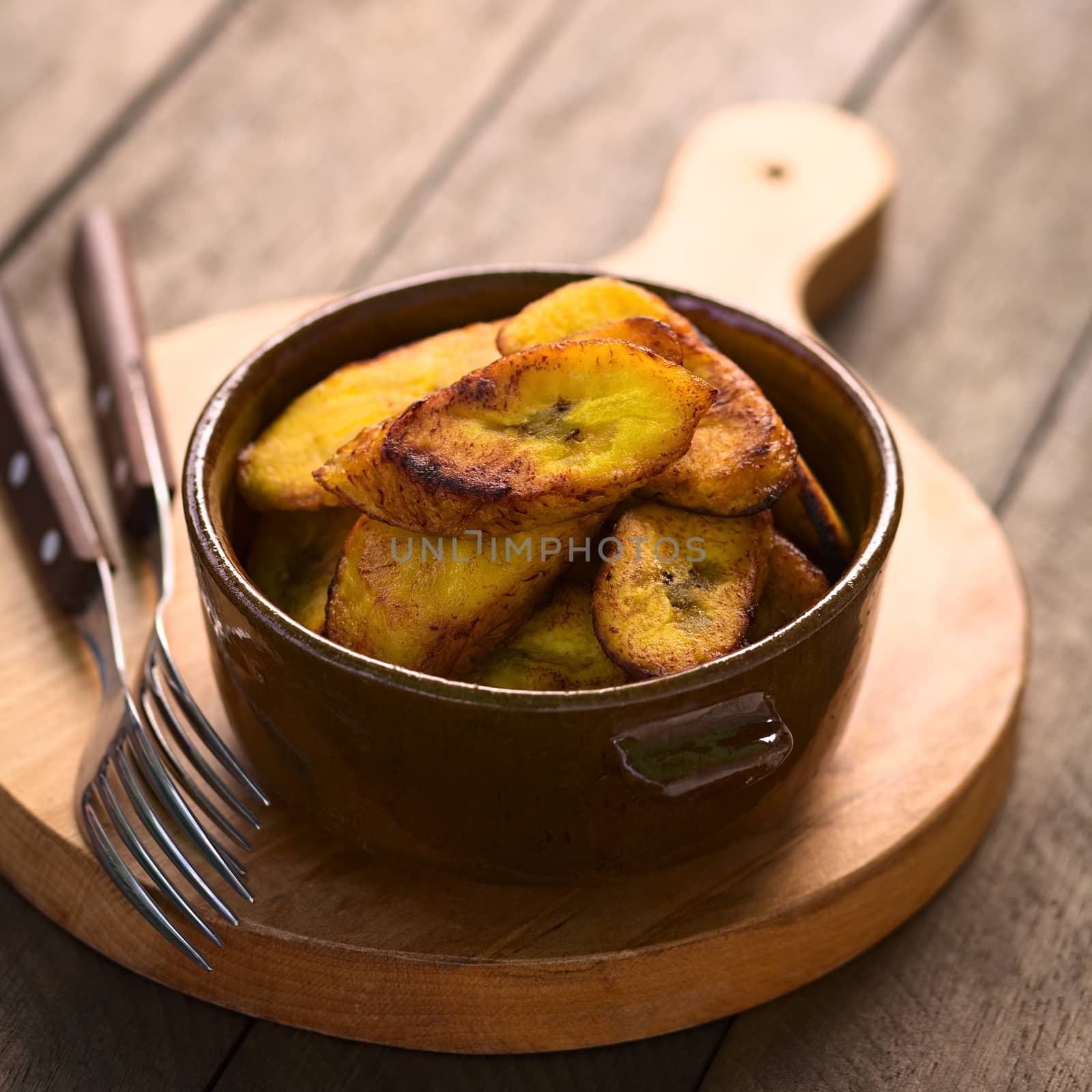 Fried slices of the ripe plantain in bowl, which can be eaten as snack or is used to accompany dishes in some South American countries (Selective Focus, Focus on the front of the upper plantain slice)