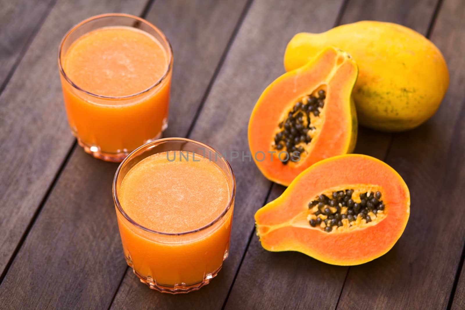 Two glasses of freshly prepared papaya juice with papaya fruits on the side (Selective Focus, Focus into the middle of the first juice) 