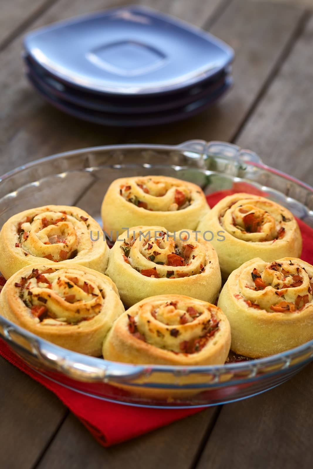 Freshly baked homemade rolls filled with tomato, ham and herbs on glass plate (Selective Focus, Focus on the middle of the roll in the middle) 