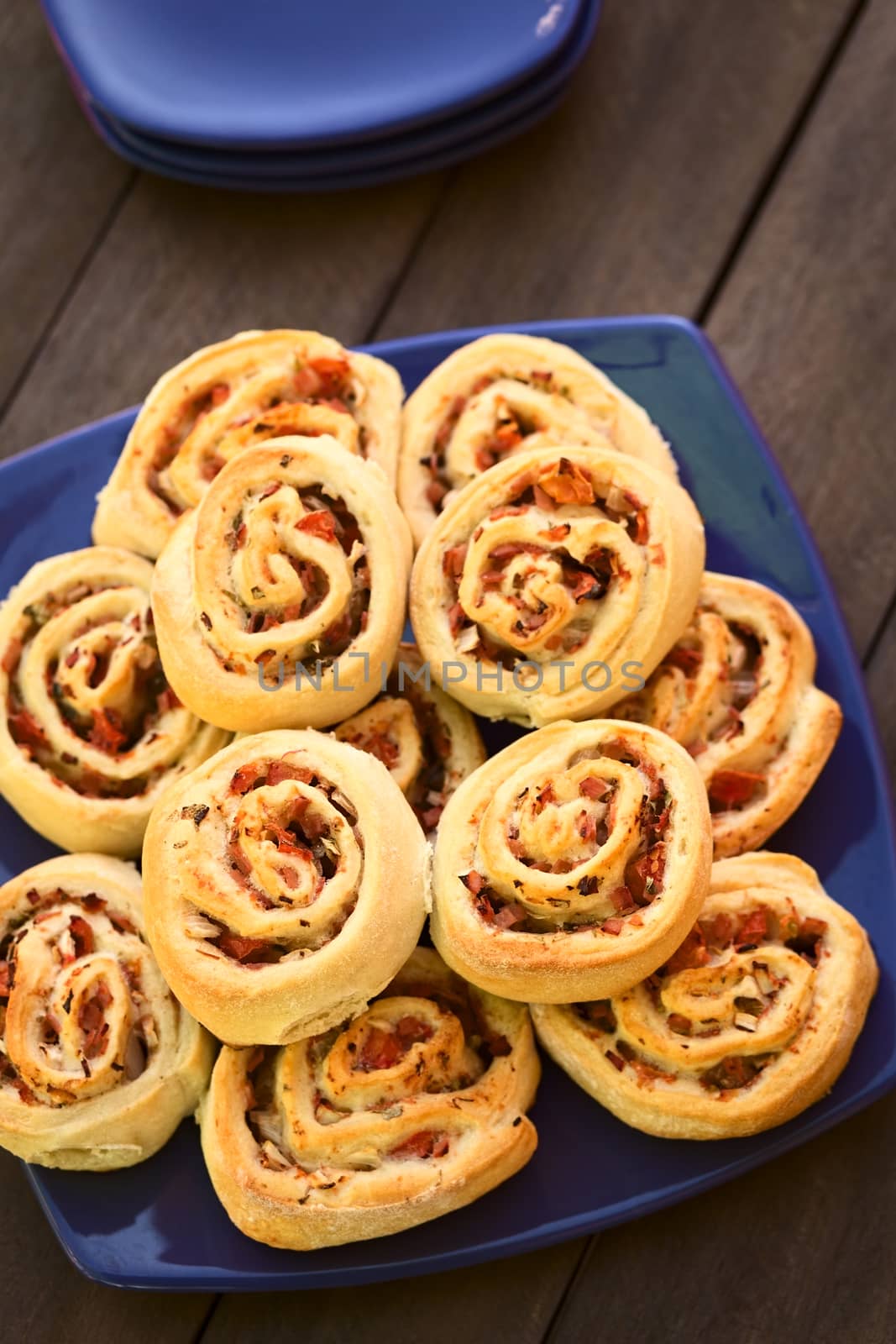 Freshly baked homemade rolls filled with tomato, ham and herbs on blue plate (Selective Focus, Focus on the first two rolls on the top) 