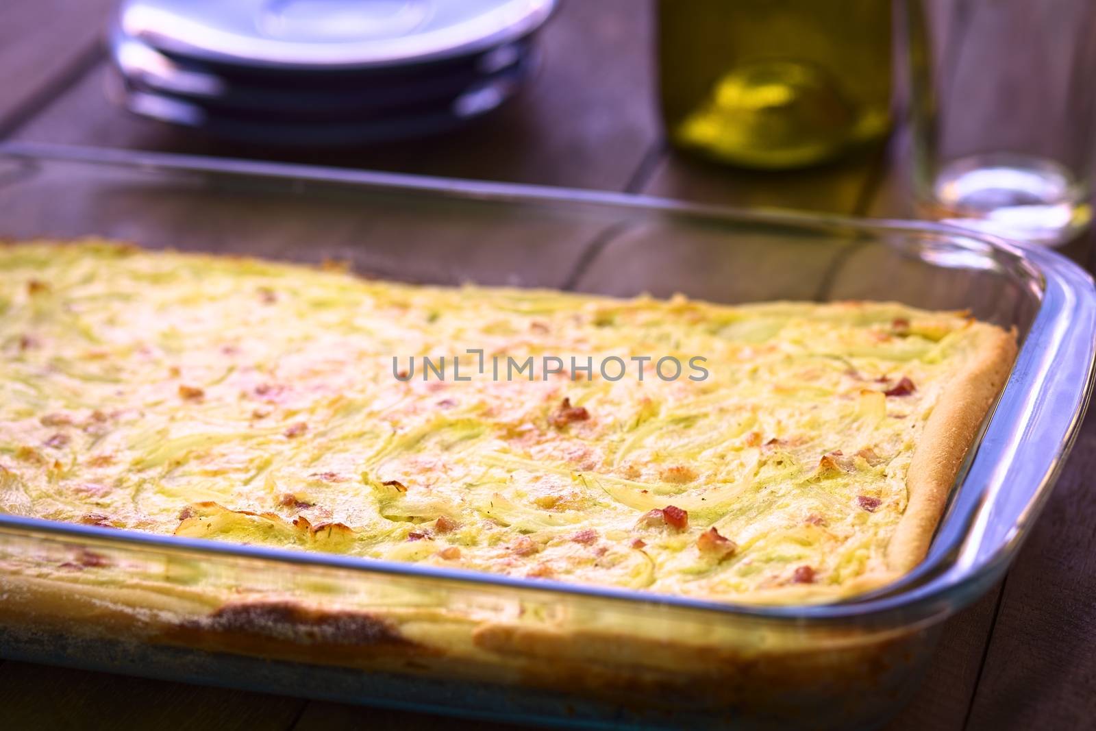 Traditional German Zwiebelkuchen or onion cake, made of a yeast dough and topped with onions and bacon in cream sauce in a glass baking pan (Very Shallow Depth of Field, Focus one third into the image) 