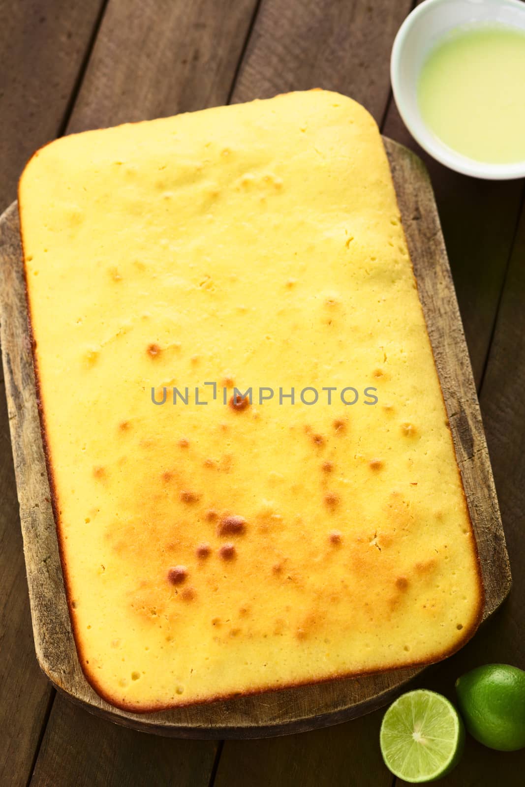 Fresh homemade key lime cake on wooden board with lime icing and key limes on the side (Selective Focus, Focus one third into the cake)