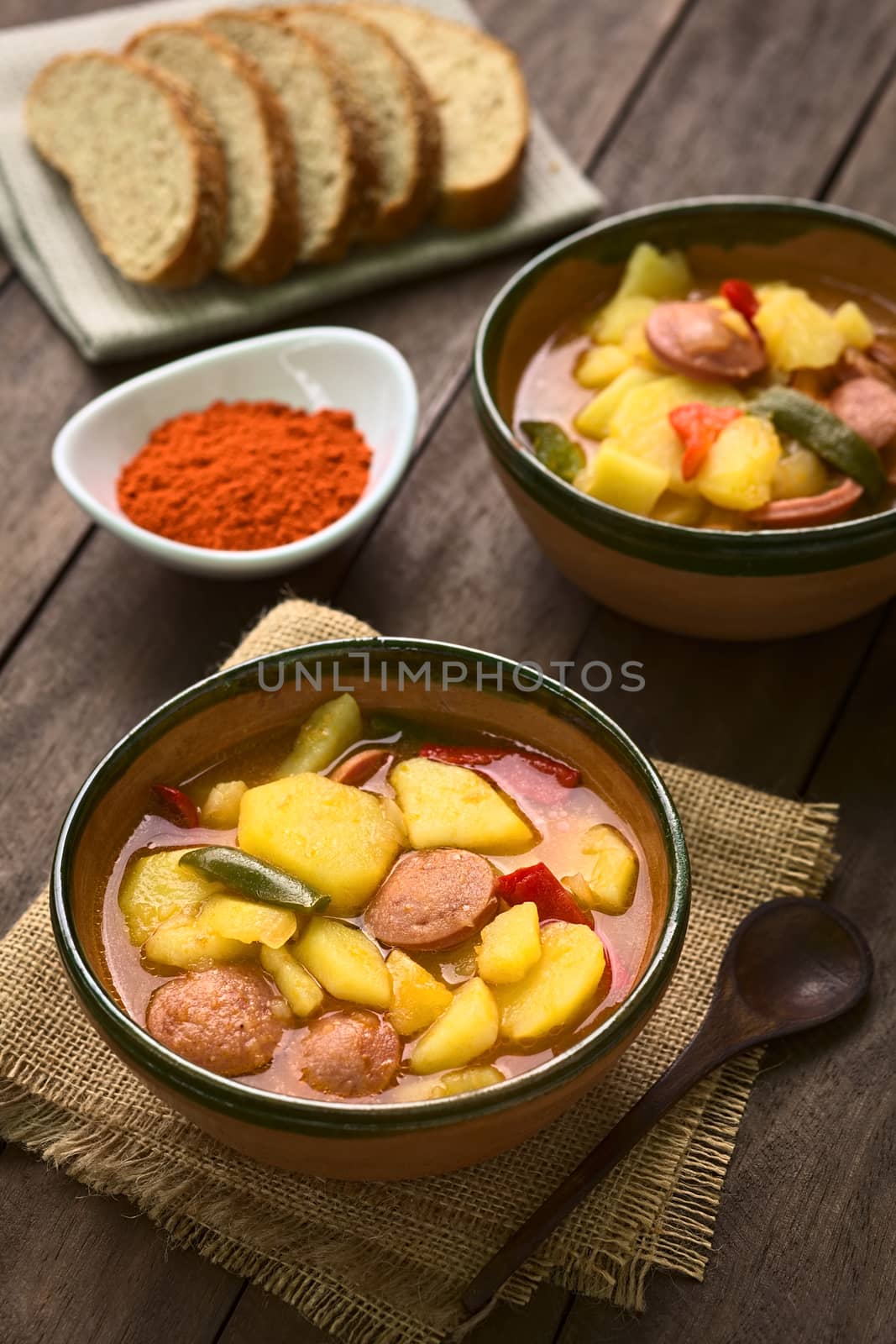 Two bowls of the Hungarian dish called Paprikas Krumpli (Potato with Paprika), a stew made of potato, onion, pepper, tomato and sausage, seasoned with the Hungarian paprika and salt (Selective Focus, Focus in the middle of the dish in the first bowl) 