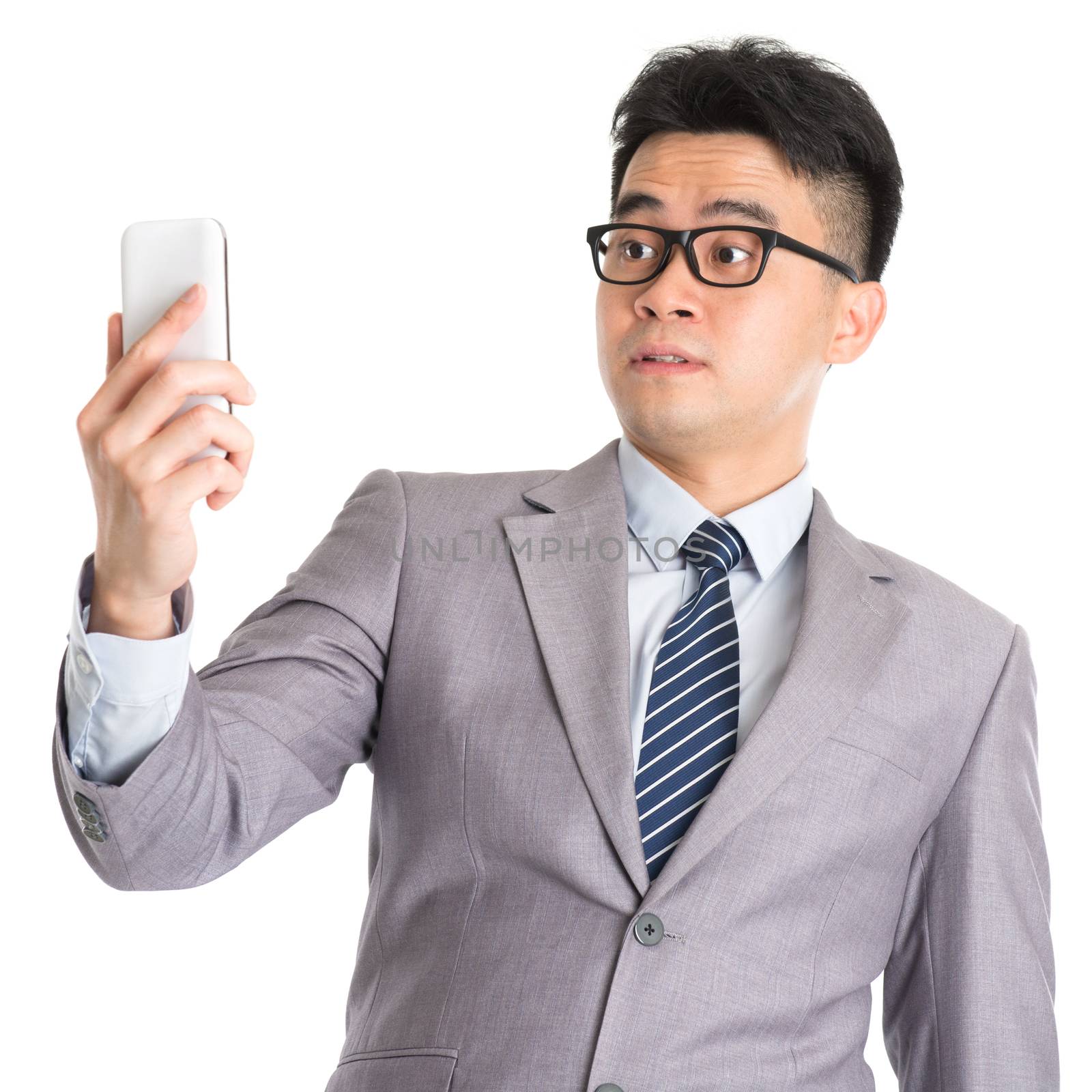 Asian business man with shocked facial expression while looking at smartphone, isolated on white background.