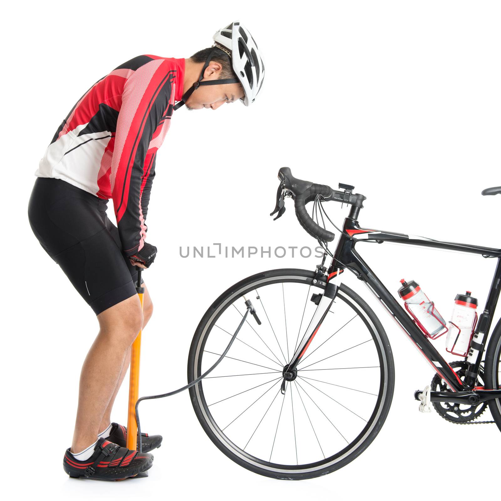 Asian cyclist pumping air to bike tire, using manual air-pump, isolated on white background.