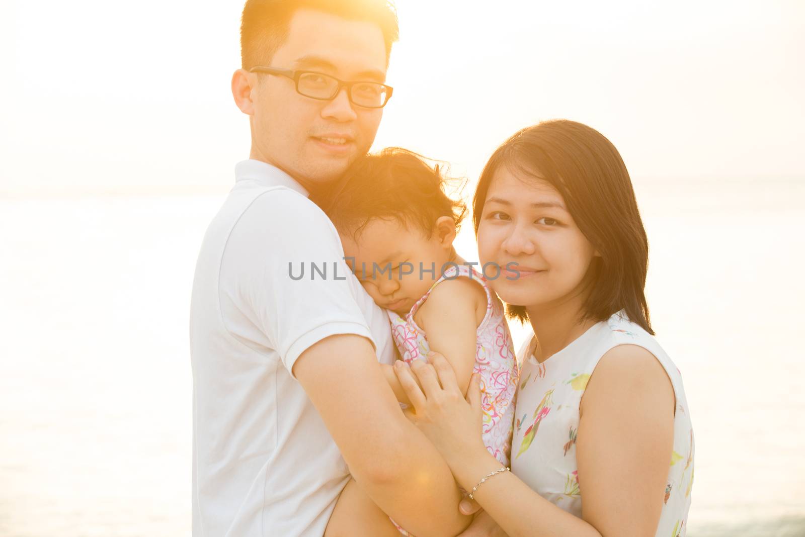 Portrait of beautiful Asian family outdoor beach vacation, during summer sunset, natural sunlight with flare.