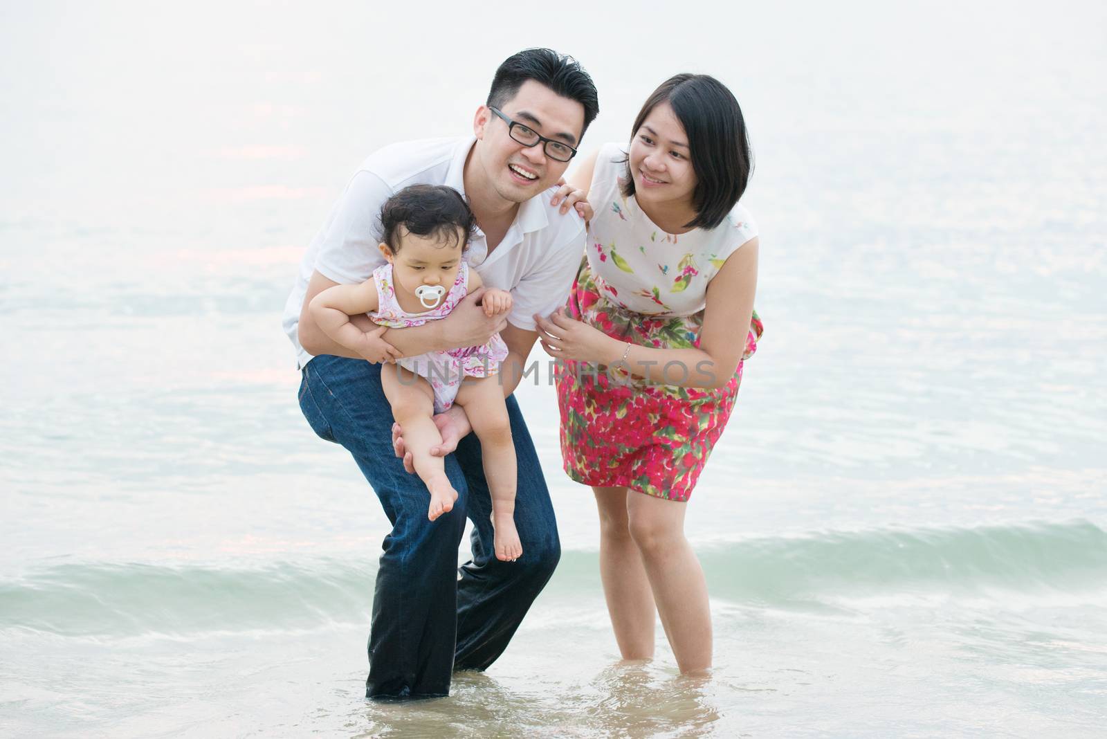 Happy Asian family outdoor on sand beach, vacation during summer, natural sunset sunlight.