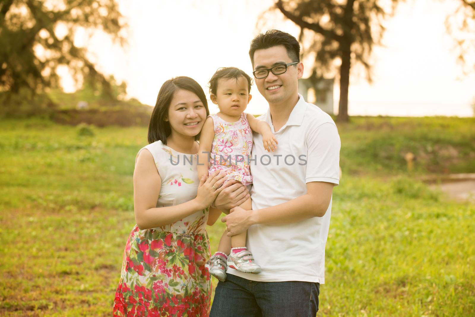 Happy Asian family portrait. Outdoor playing time during summer sunset.