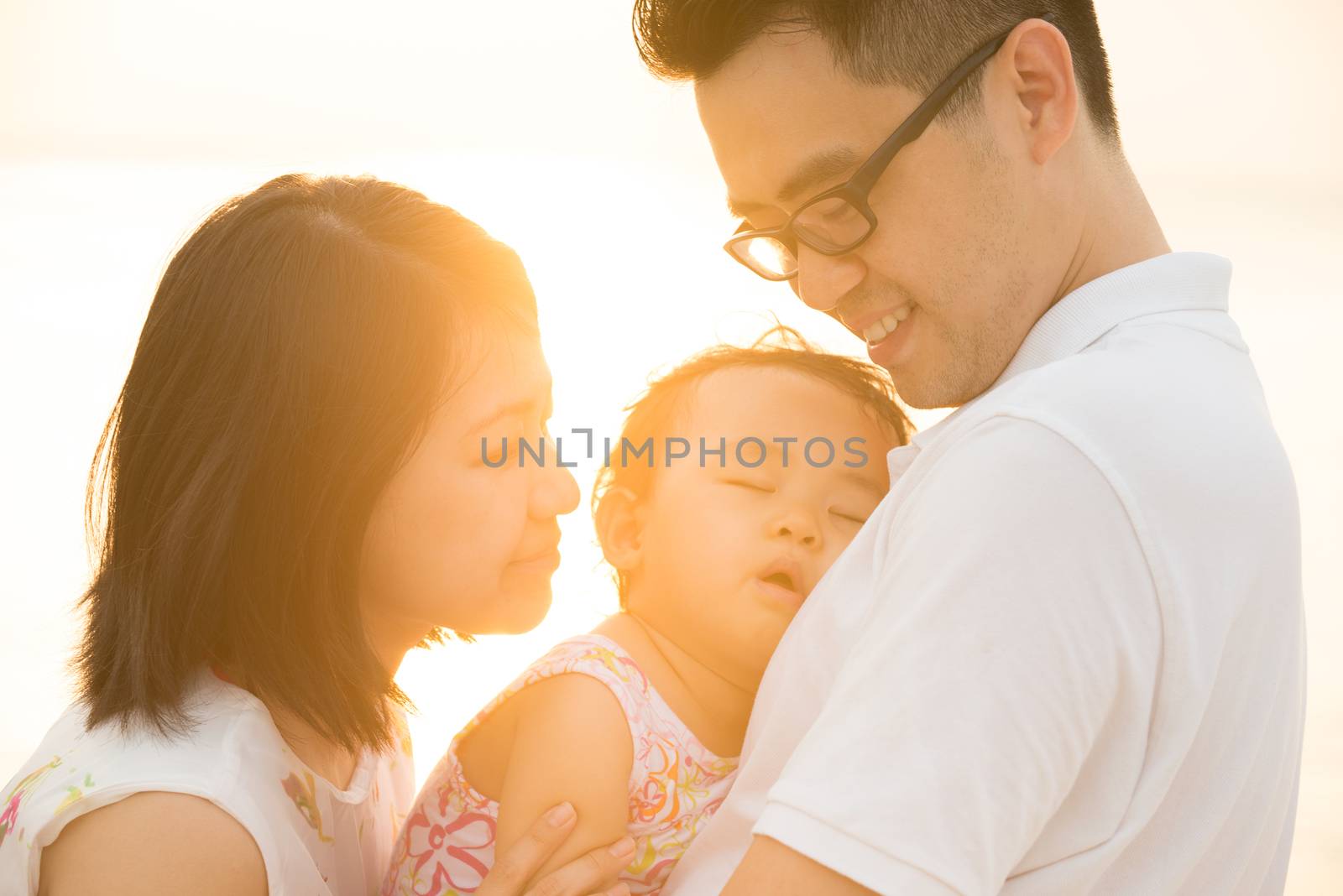 Portrait of happy Asian family outdoor beach vacation, during summer sunset, natural sunlight with flare.