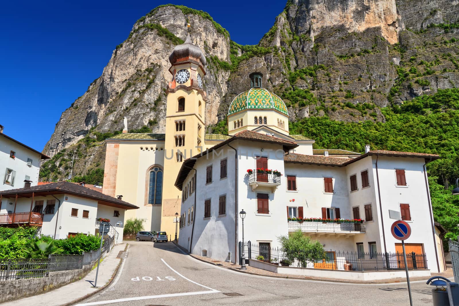 church in Mezzacorona village on sunny summer day with mountains in the background, Trentino, Italy