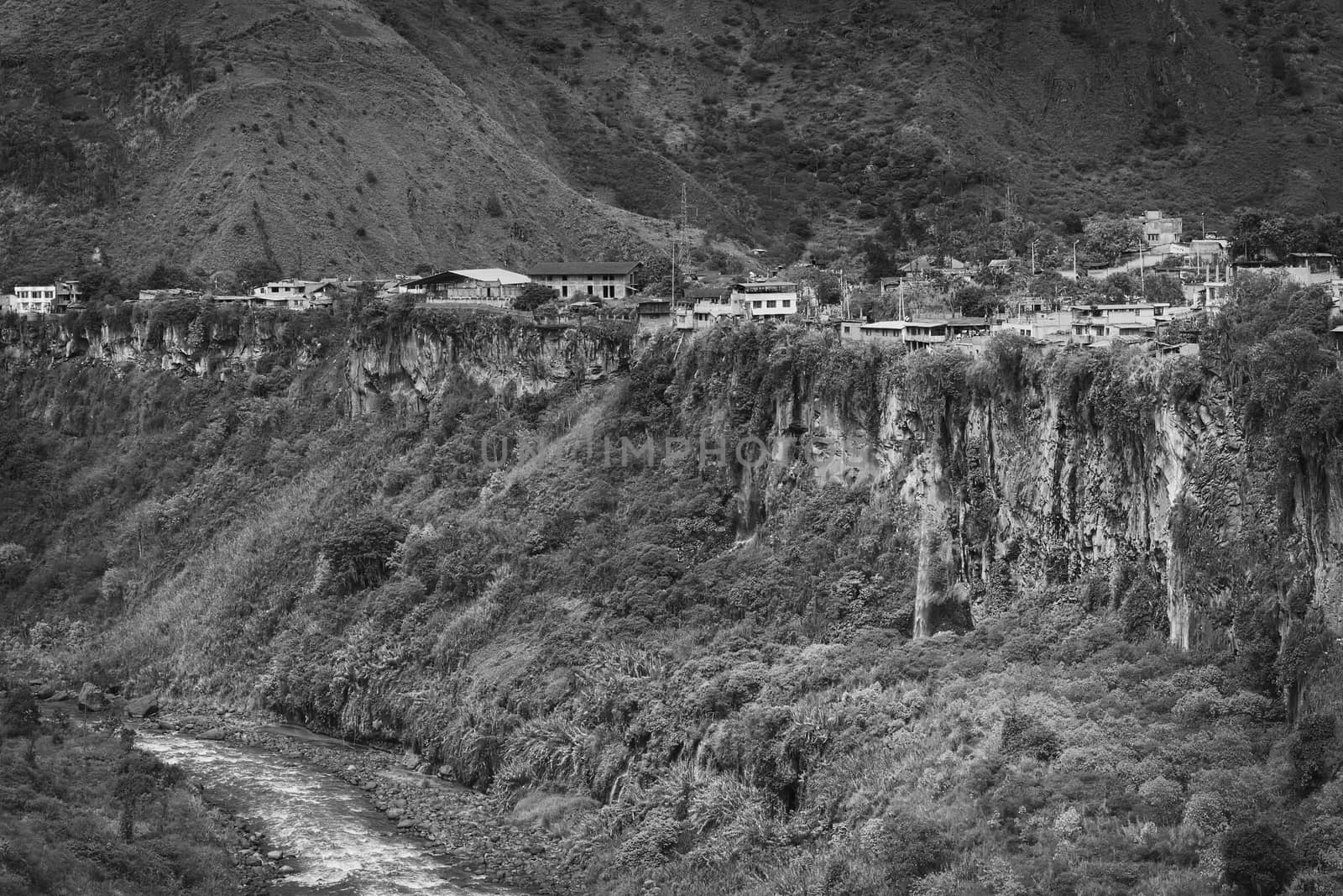 Monochrome image of the Pastaza River and the small town of Banos in Ecuador on the cliffs with some waterfalls dropping down 