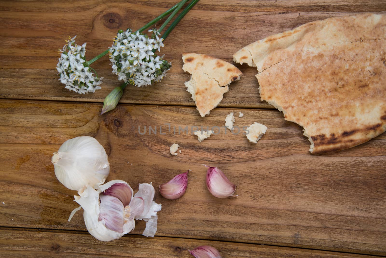 Fresh garlic bulb and flowers and naan bread on kitchen table