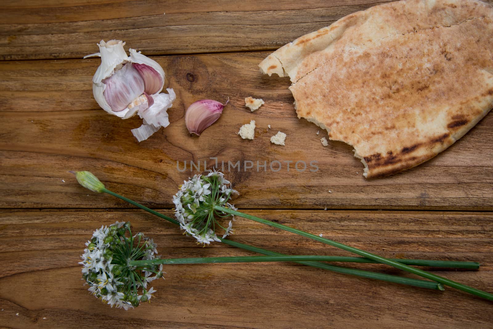 Fresh garlic bulb and flowers and naan bread on kitchen table