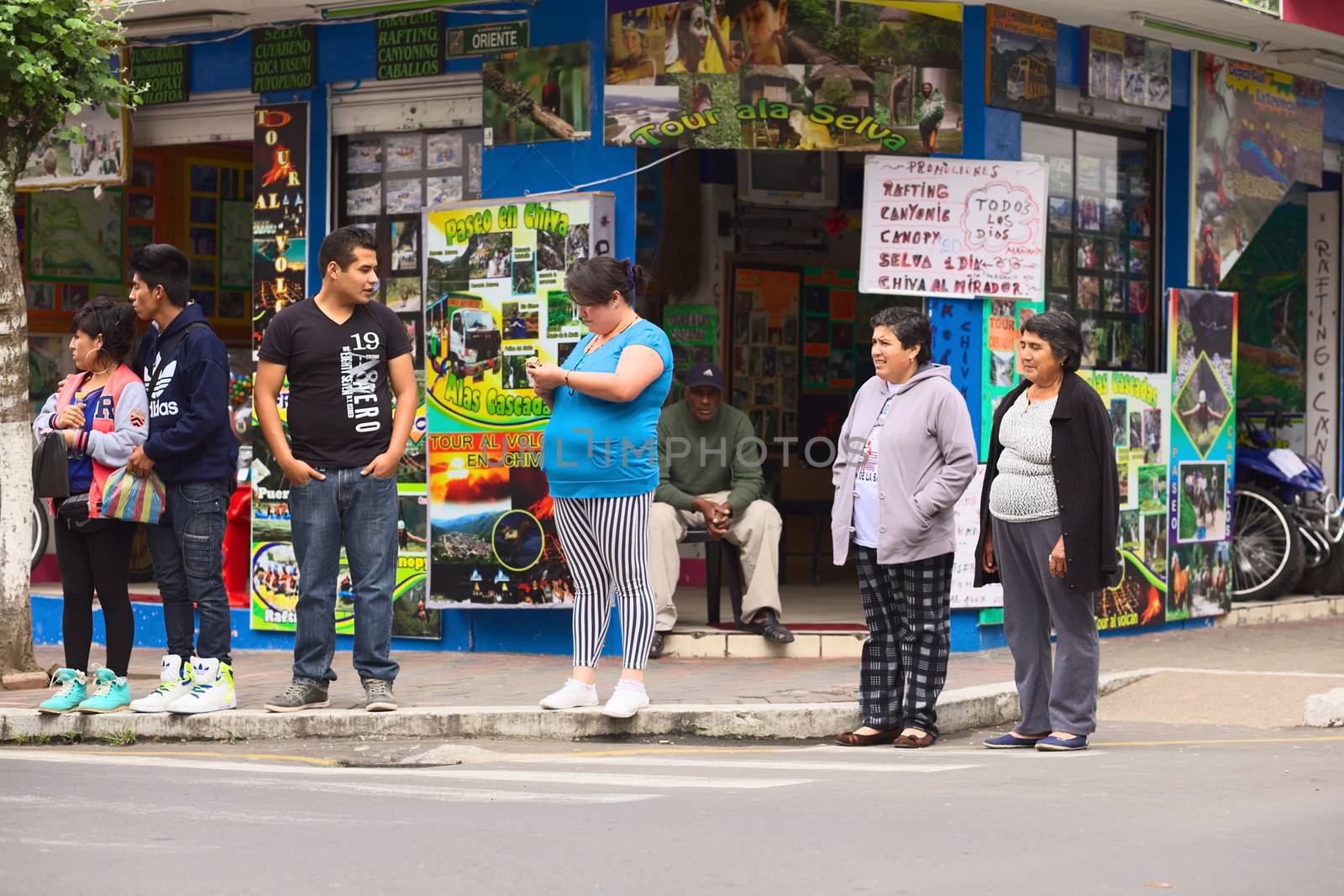 BANOS, ECUADOR - FEBRUARY 22, 2014: Unidentified people on the corner of the streets Oriente and Pedro Vicente Maldonado with the Siseaventours Travel Agency in the back on February 22, 2014 in Banos, Ecuador. Banos is a small touristy town which is mainly known for its various outdoor activities.