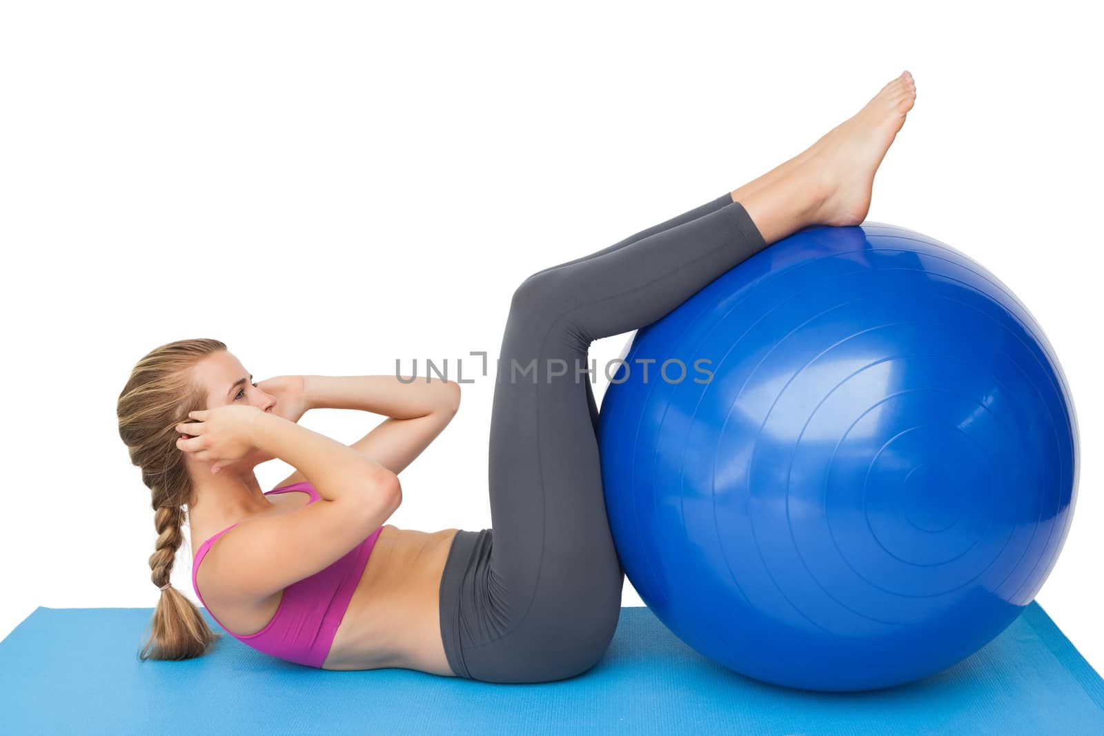 Side view of a fit young woman exercising with fitness ball over white background