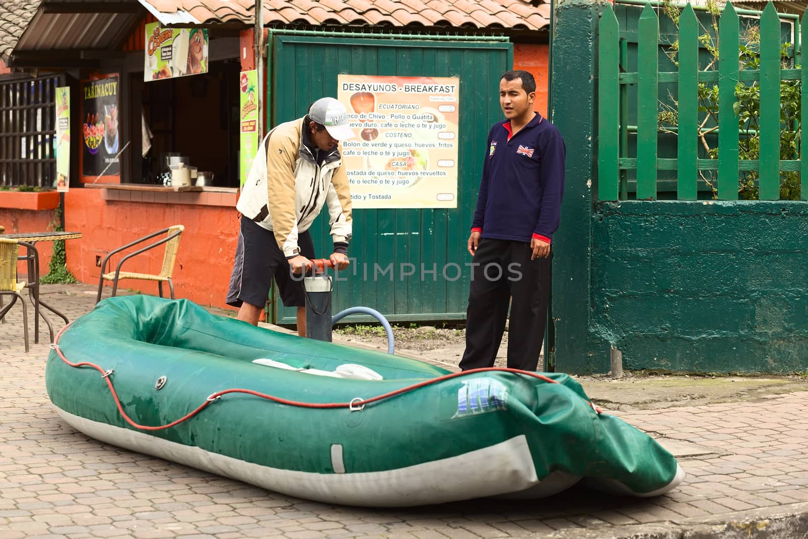 BANOS, ECUADOR - FEBRUARY 25, 2014: Unidentified people inflating a rubber boat on 16 de Diciembre Street on February 25, 2014 in Banos, Ecuador. Banos is known and visited for its various outdoor activities, such as rafting, canyoning, bridge jumping, etc. 