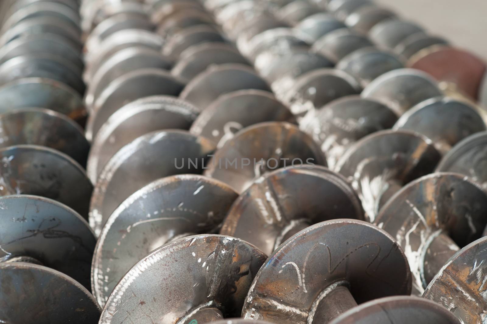 Unfinished screw conveyor parts at a factory. Very shallow depth of field with the nearest part of the screws in focus.