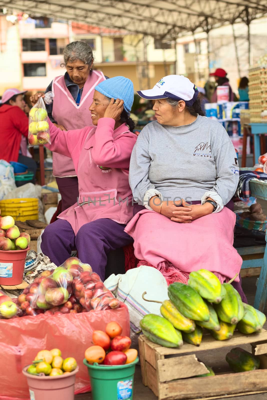 BANOS, ECUADOR - FEBRUARY 26, 2014: Unidentified female vendors on the market on Plaza 5 de Junio on February 26, 2014 in Banos, Ecuador. On the market, which is held every Wednesday, Friday and Sunday, mainly fruits and vegetables are being offered, with a few stands of dairy and meat products. 