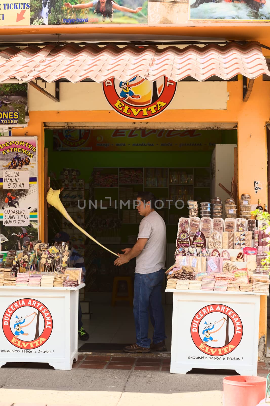 BANOS, ECUADOR - FEBRUARY 26, 2014: Unidentified young man preparing the traditional taffy of Banos called Melcocha (traditionally made of sugar cane) at the Dulceria Artesanal Elvita on Ambato Street on February 26, 2014 in Banos, Ecuador. 