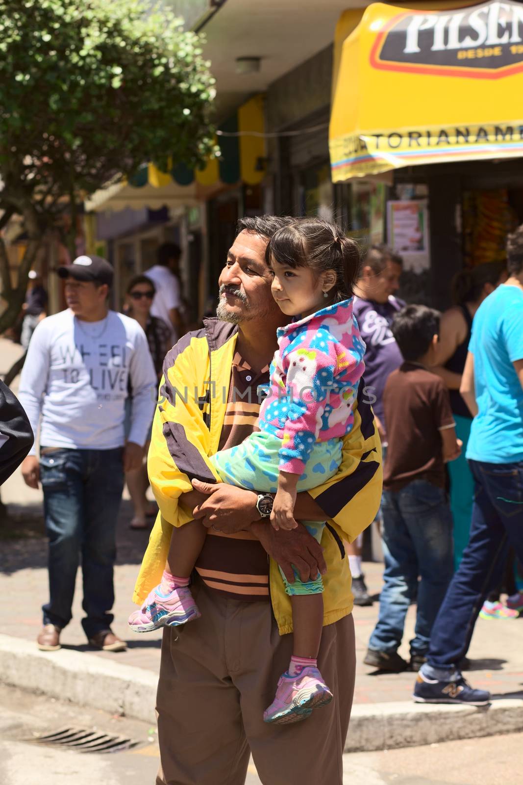 BANOS, ECUADOR - MARCH 2, 2014: Unidentified man and girl watching the carnival parade on Ambato Street on March 2, 2014 in Banos, Ecuador.