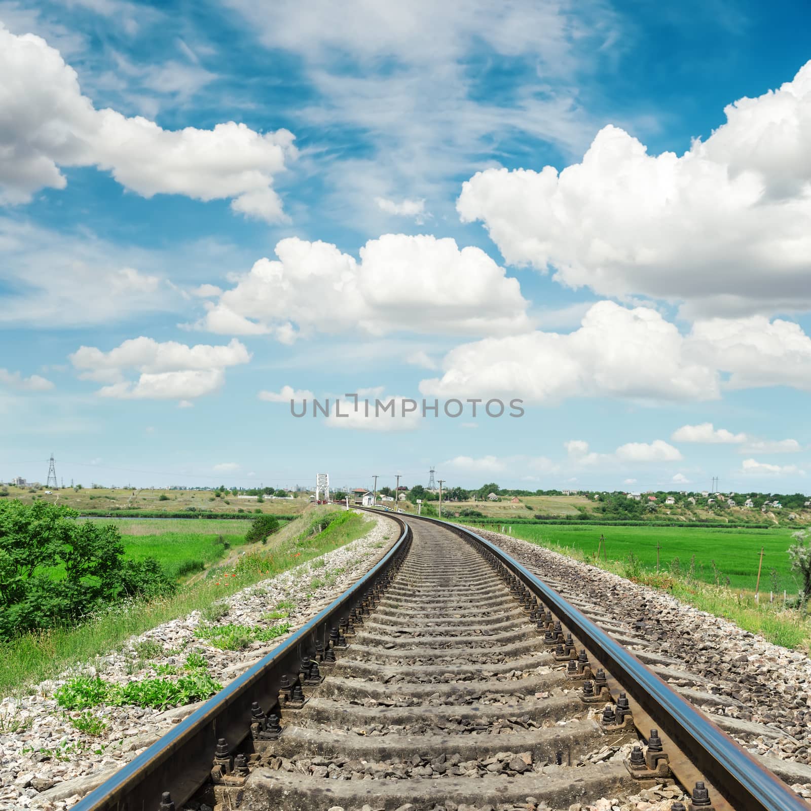 railroad to horizon in green landscape and cloudy sky
