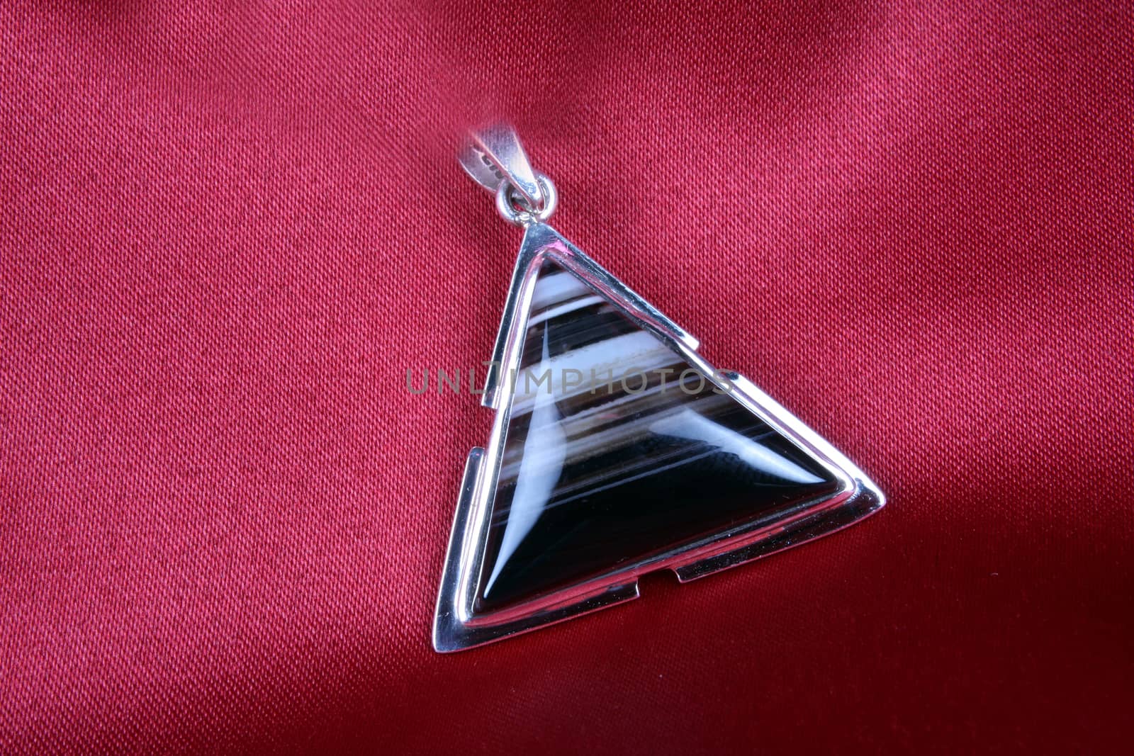 An antique Triangular Silver Pendant with Jasper stone kept on a crimson cloth