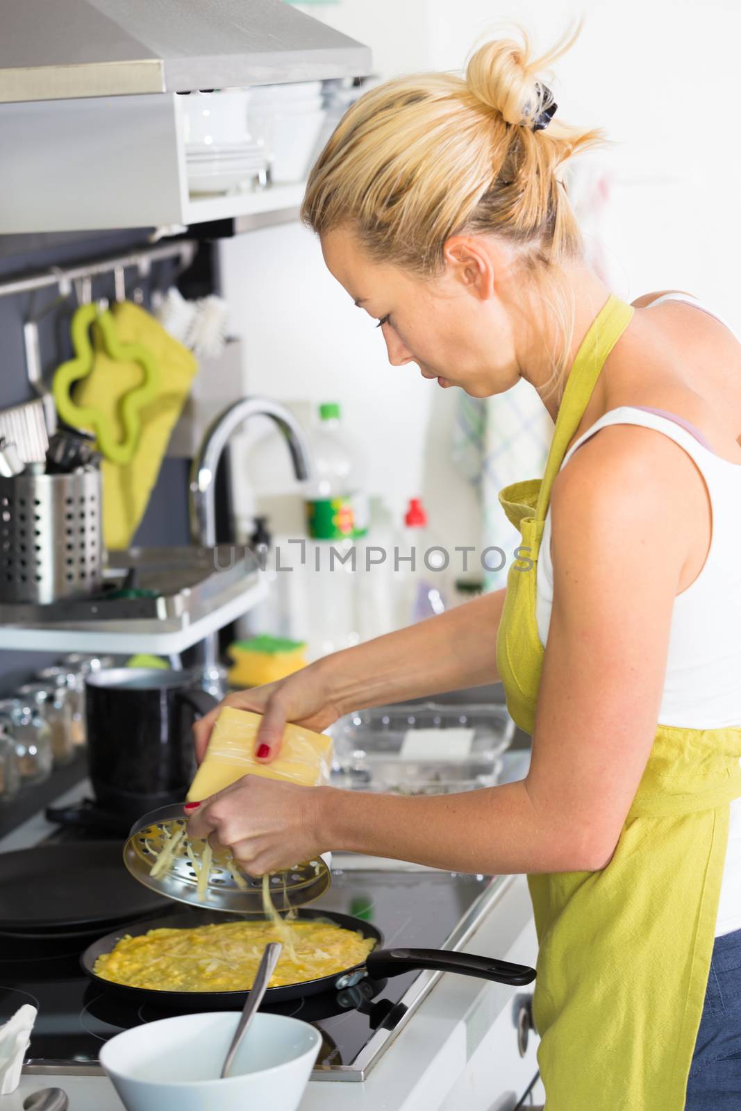 Young Woman Cooking. Healthy Mediterranean Breakfast - Home Made Egg Omlete Stuffed with Dried Tomatoes in Olive Oil and Cheese. Healthy Lifestyle. 