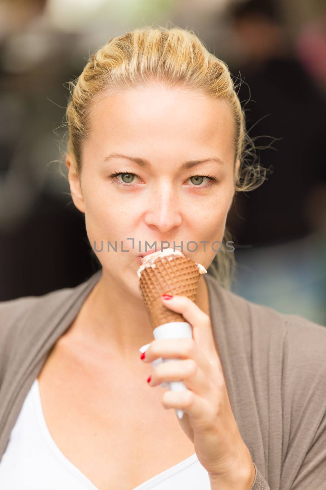 Casual blonde lady licking icecream in cone.
