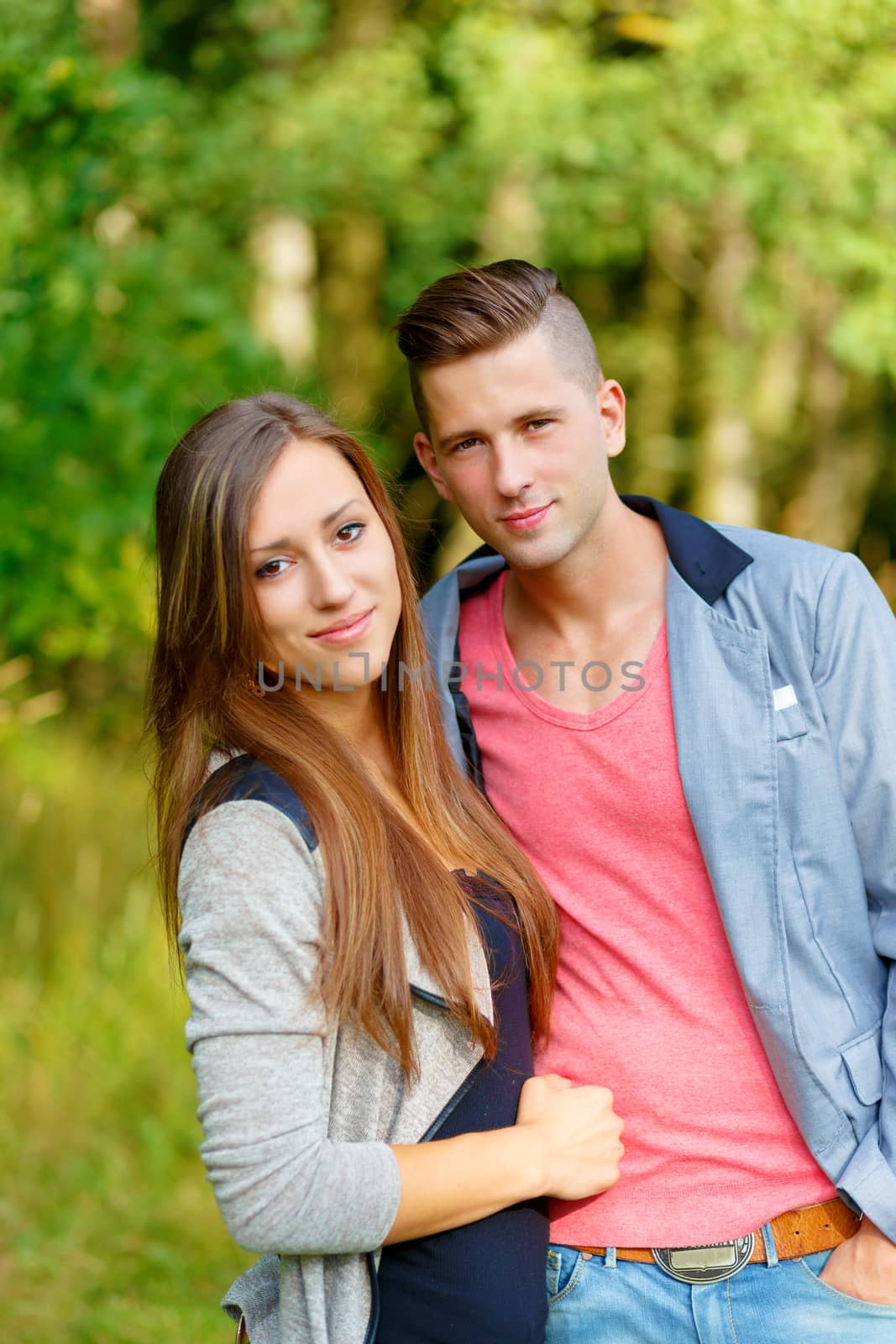 Happy smiling young couple embracing outdoor at sunny day