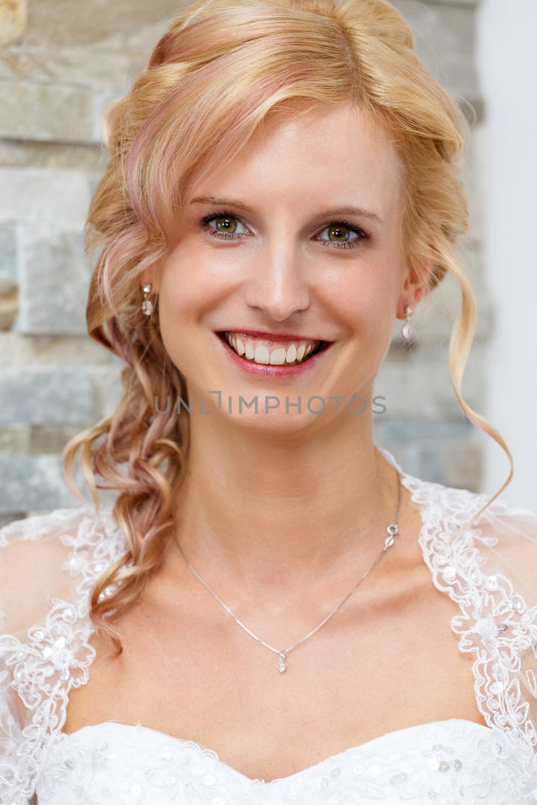 home portrait of beautiful blonde smiling bride dressed to white clothe