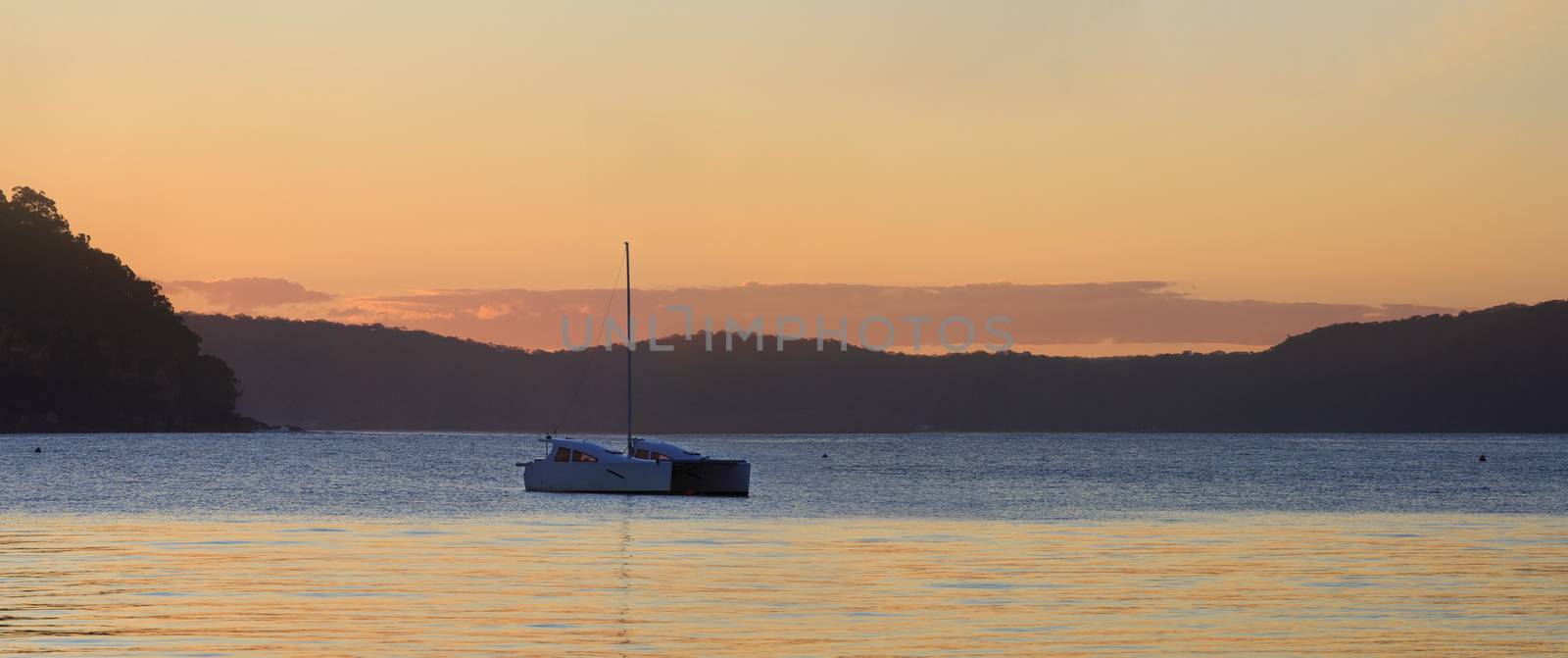 Simple and serenel sunset on the last day of winter at beautiful travel destination Palm Beach, Sydney - a sign of the warm days ahead.  Catamaran on the water and views to West Head  Patonga and Hawkesbury, from Pittwater side.