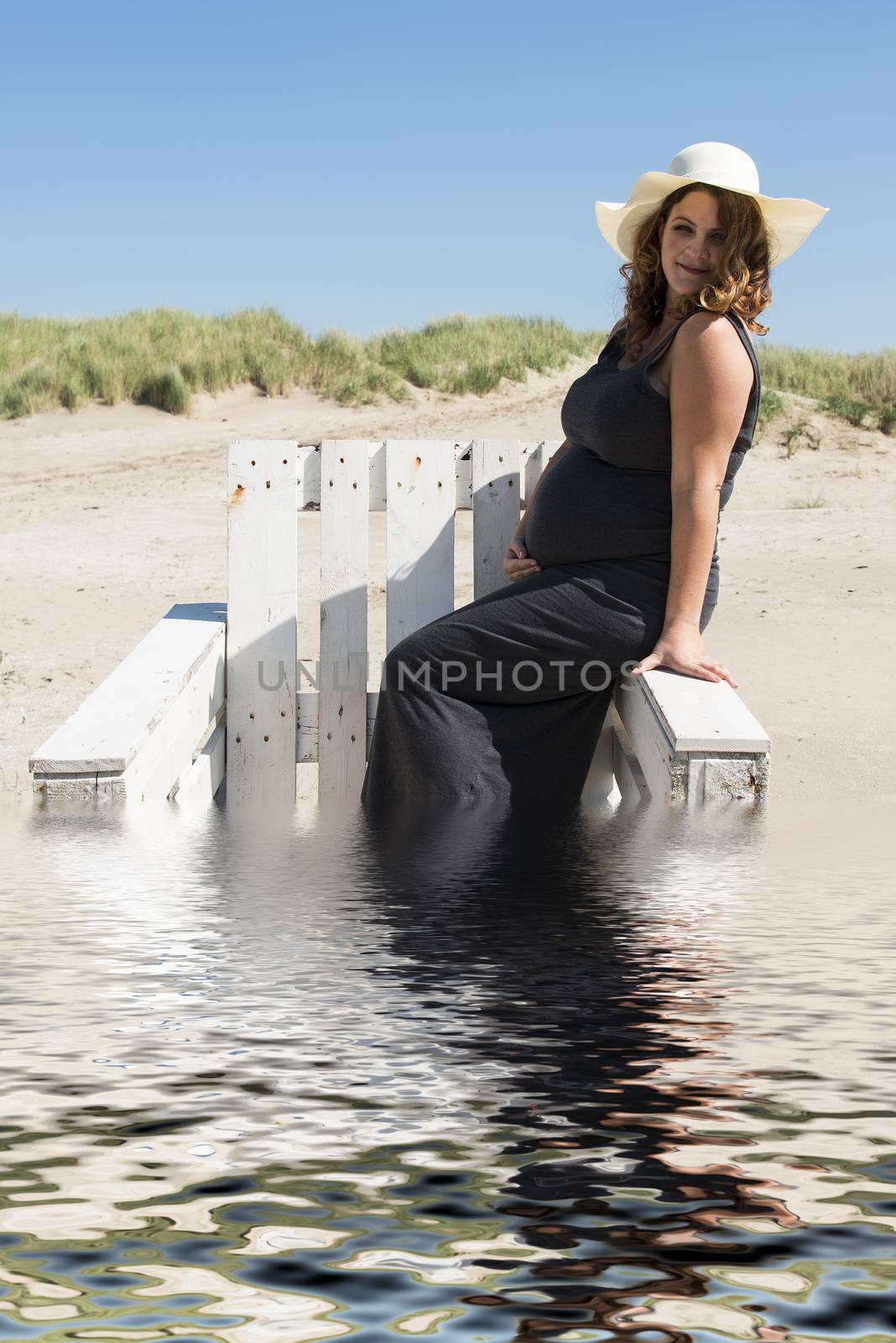 pregnant woman sitting on chair on the beach in the water