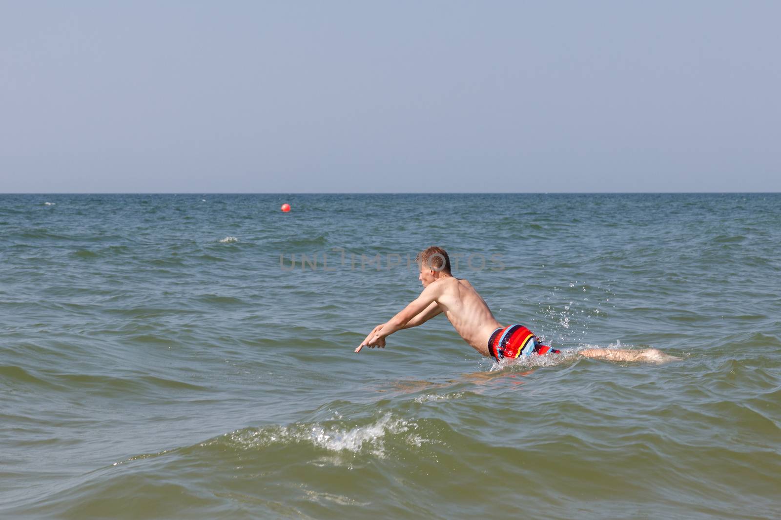 A teen boy juming into water to swim