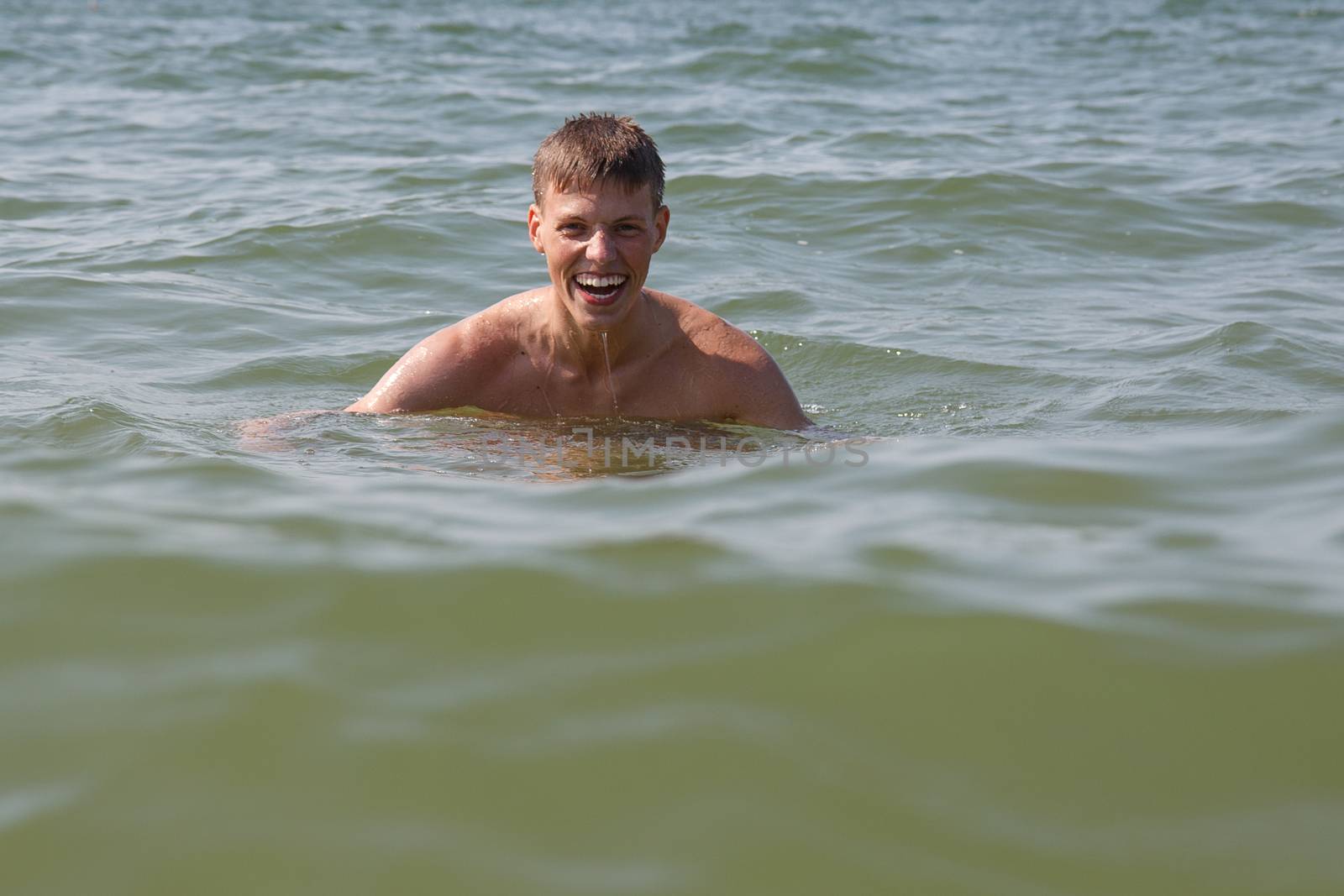 A man swimming in the ocean and smiling