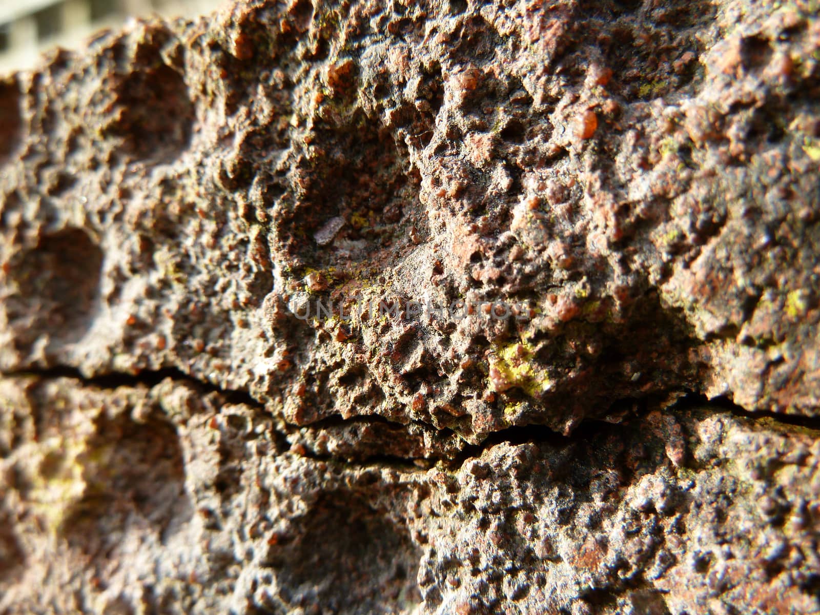 Old cracked pitted brown stone in bright light